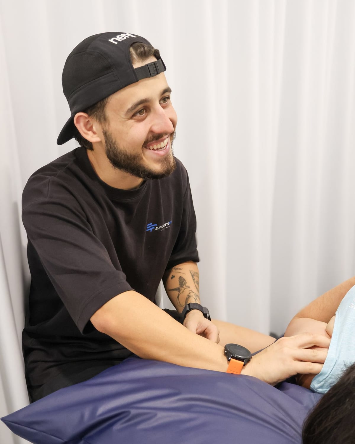 Practitioner and patient laughing mid-treatment at SportsFit Five Dock