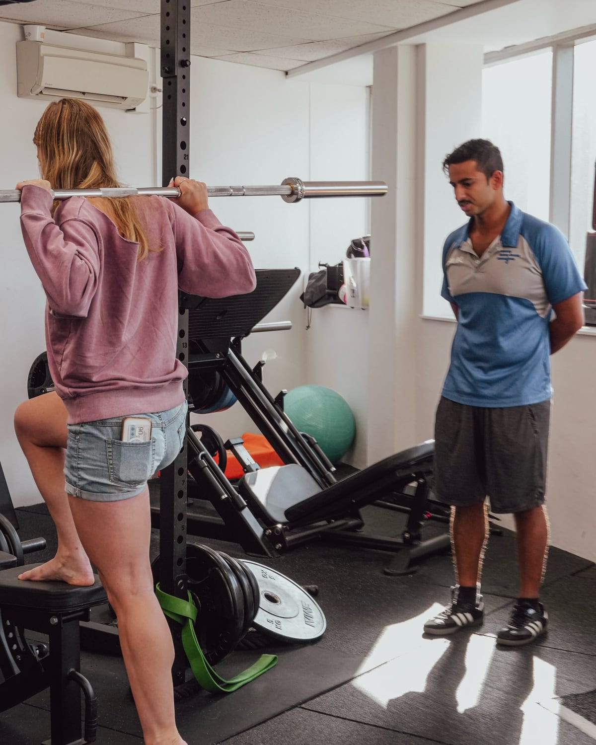 Physiotherapist supervising a patient lifting in the squat rack at SportsFit Five Dock