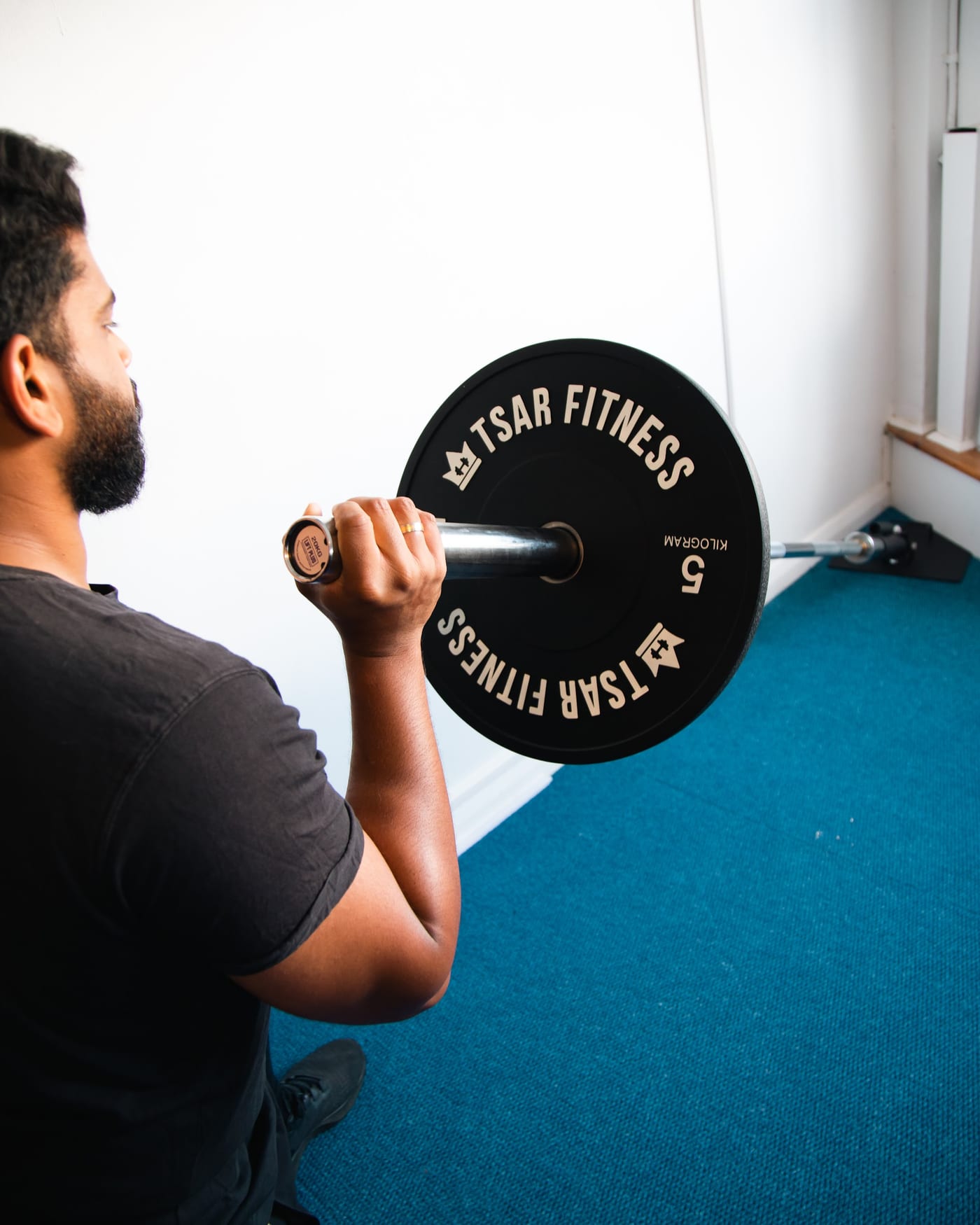 Man performing a half-kneeling landmine press in the SportsFit Five Dock gym